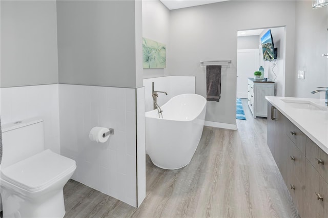 bathroom with vanity, a bath, wood-type flooring, and toilet