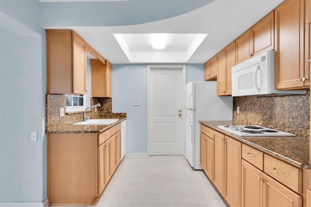 kitchen with decorative backsplash, a tray ceiling, dark stone counters, sink, and white appliances