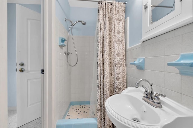 bathroom with tile walls, sink, and walk in shower