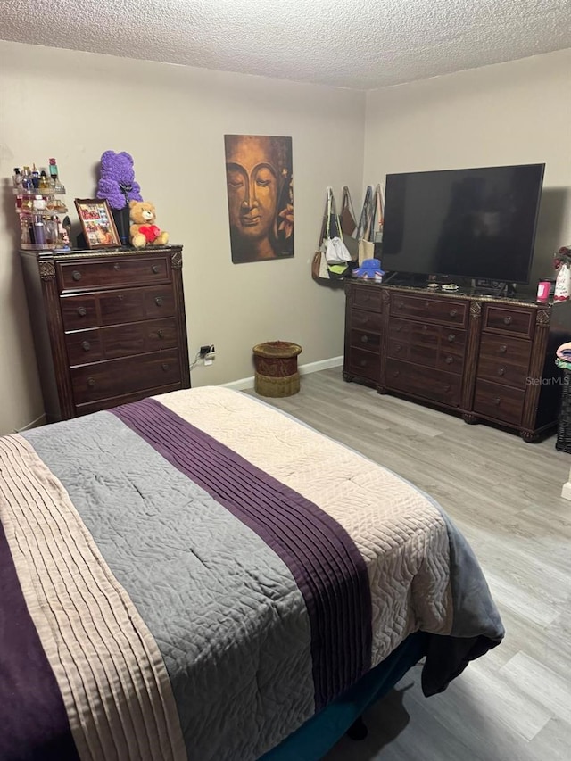 bedroom with light hardwood / wood-style flooring and a textured ceiling