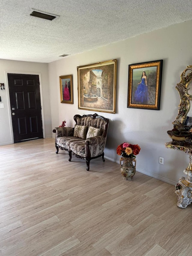 living area with a textured ceiling and light wood-type flooring