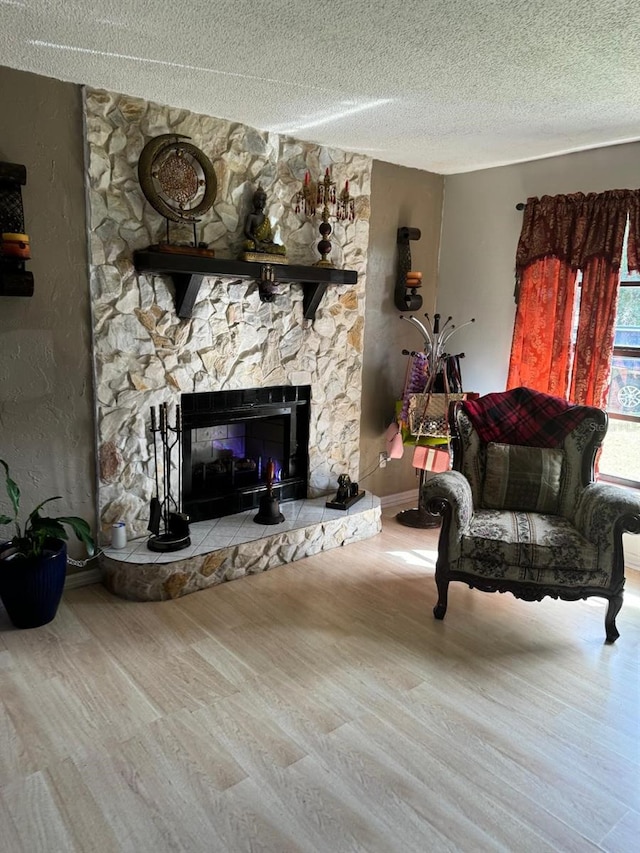 living area with a textured ceiling, wood-type flooring, and a fireplace