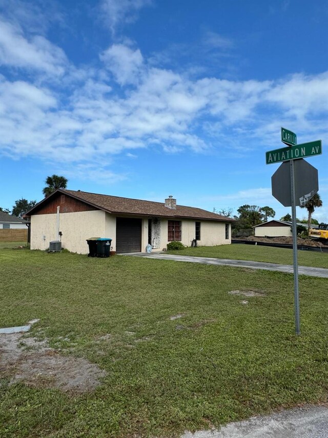 111 Carillo St NE, Palm Bay, FL 32907 - view of front facade featuring a garage, a front yard, driveway, central air condition unit, and a chimney
