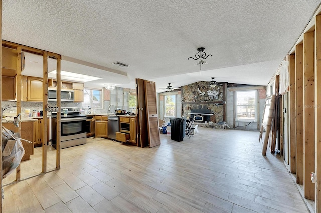 kitchen with ceiling fan, a healthy amount of sunlight, lofted ceiling, and stainless steel appliances