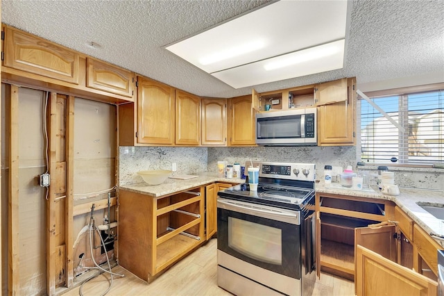 kitchen featuring stainless steel appliances, a textured ceiling, light wood-type flooring, and decorative backsplash