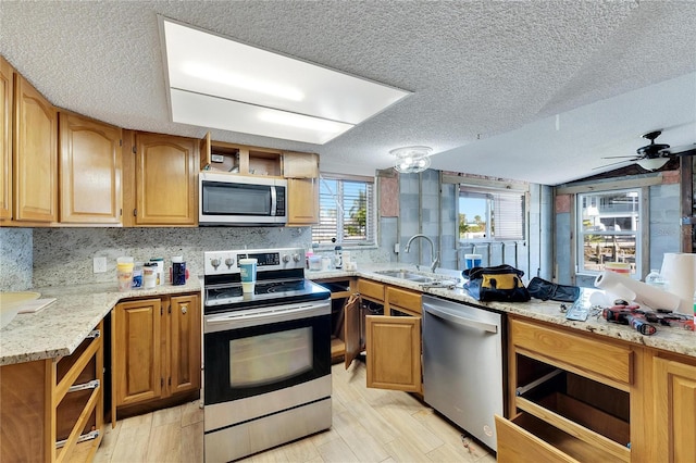 kitchen featuring ceiling fan, appliances with stainless steel finishes, a textured ceiling, light wood-type flooring, and sink