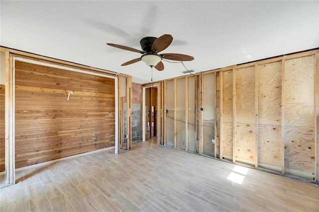 spare room featuring ceiling fan, wood walls, and light hardwood / wood-style floors