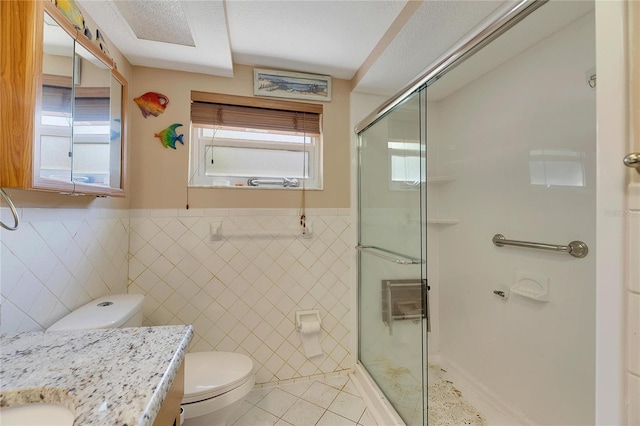 bathroom with an enclosed shower, toilet, tile patterned floors, tile walls, and vanity