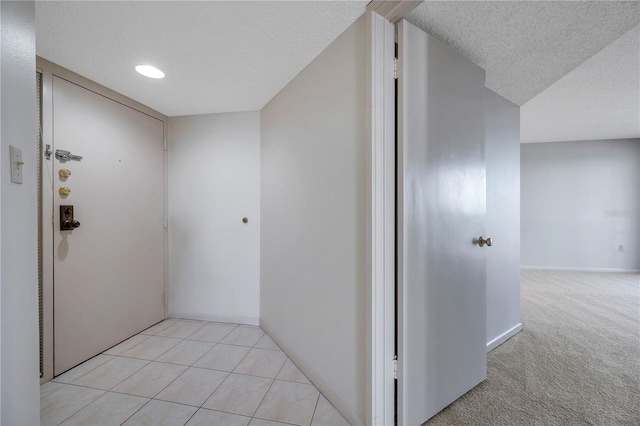 corridor featuring light carpet and a textured ceiling