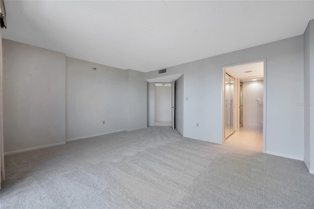 unfurnished room featuring light carpet and a textured ceiling