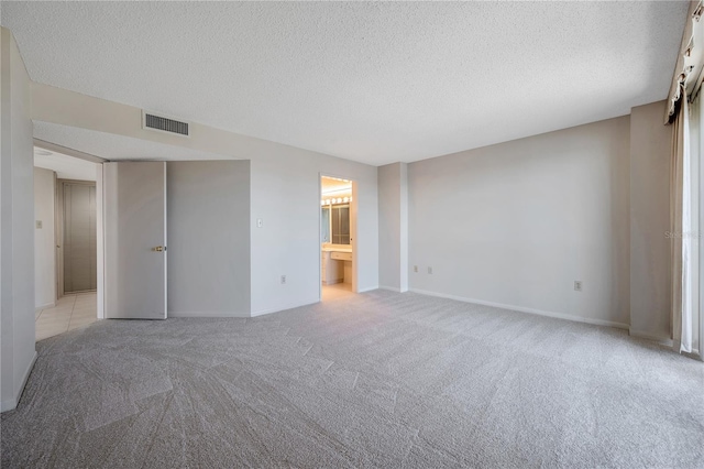 unfurnished room featuring light carpet and a textured ceiling