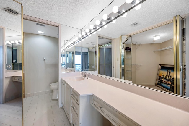 bathroom featuring vanity, toilet, a textured ceiling, and tile patterned flooring