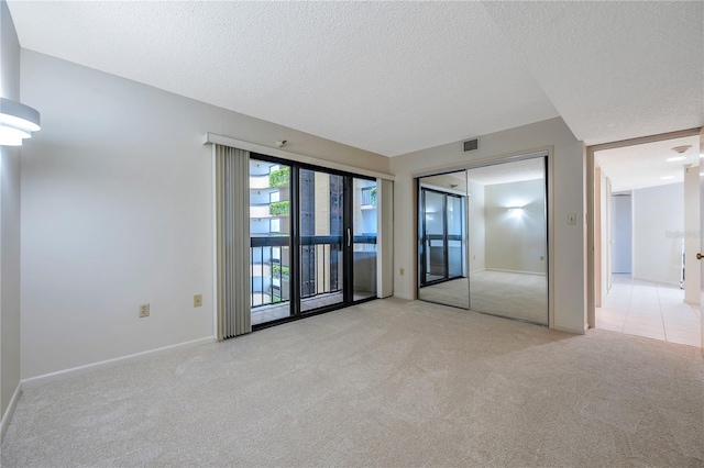 carpeted empty room with a textured ceiling