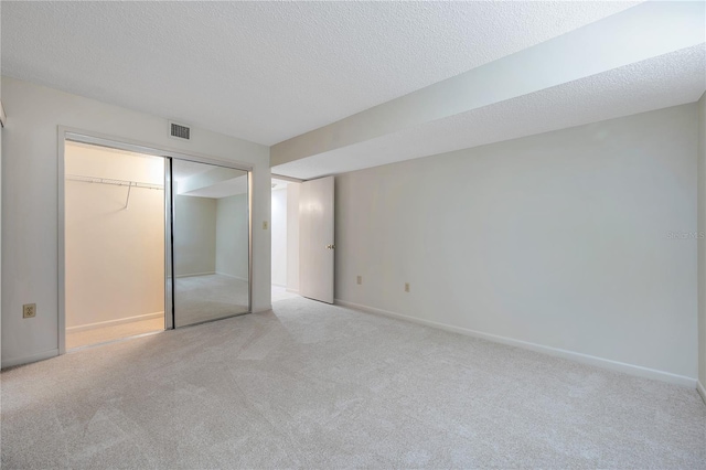 unfurnished bedroom with light carpet, a closet, and a textured ceiling