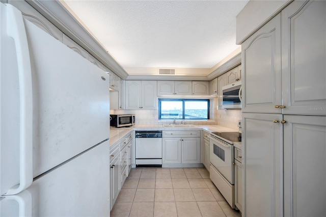 kitchen featuring white appliances, tasteful backsplash, sink, white cabinets, and light tile patterned floors