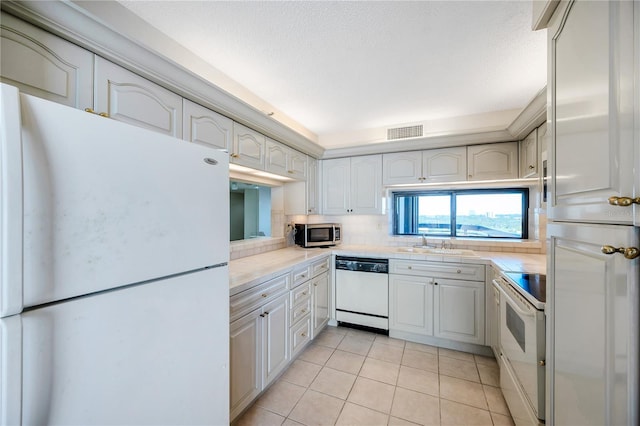 kitchen with sink, light tile patterned floors, a textured ceiling, white appliances, and tasteful backsplash