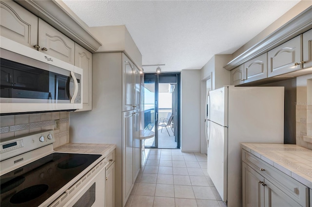 kitchen featuring a textured ceiling, light tile patterned floors, range with electric cooktop, and white refrigerator