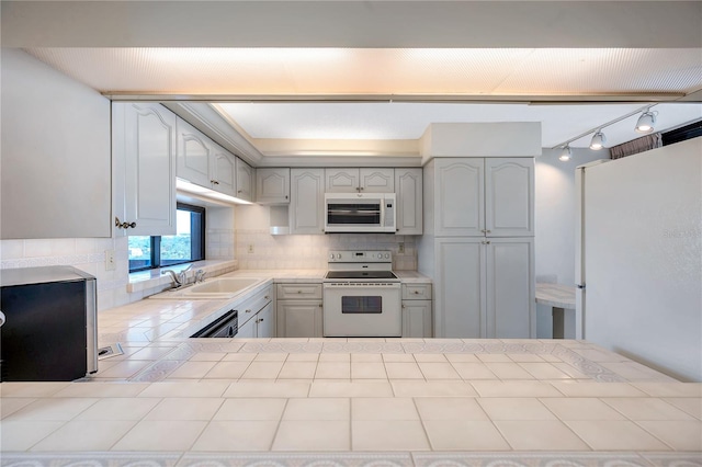 kitchen featuring kitchen peninsula, tasteful backsplash, white cabinetry, sink, and white appliances