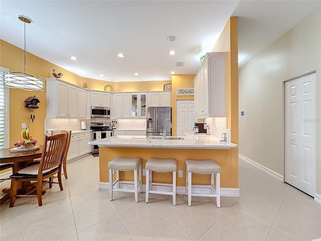 kitchen featuring appliances with stainless steel finishes, sink, a kitchen bar, hanging light fixtures, and white cabinets