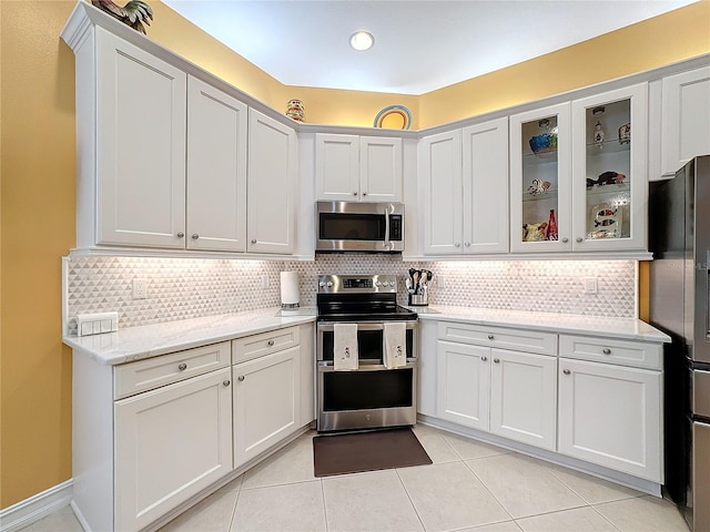 kitchen with stainless steel appliances, light tile patterned floors, light stone counters, and backsplash