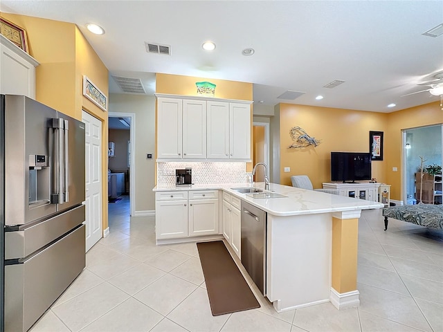 kitchen with kitchen peninsula, sink, white cabinetry, light tile patterned floors, and appliances with stainless steel finishes