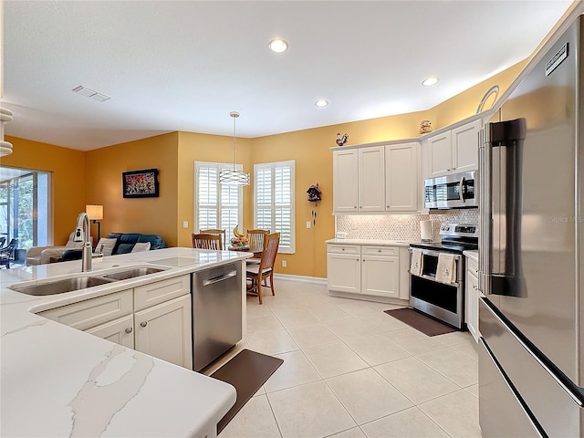 kitchen with appliances with stainless steel finishes, white cabinets, light stone countertops, and decorative light fixtures