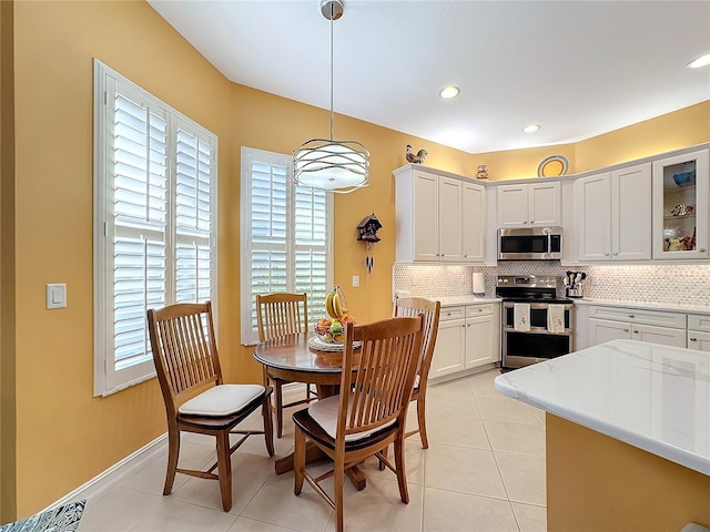 kitchen featuring light stone countertops, white cabinetry, stainless steel appliances, pendant lighting, and light tile patterned floors