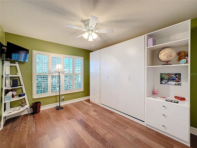 bedroom with ceiling fan, a textured ceiling, and light hardwood / wood-style flooring