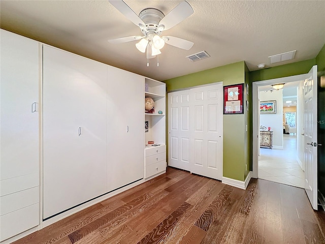 unfurnished bedroom featuring ceiling fan, a textured ceiling, and dark hardwood / wood-style flooring