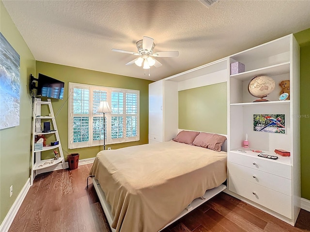 bedroom with a textured ceiling, dark wood-type flooring, and ceiling fan