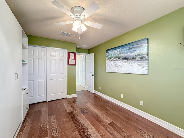 unfurnished bedroom featuring a closet, a textured ceiling, dark wood-type flooring, and ceiling fan