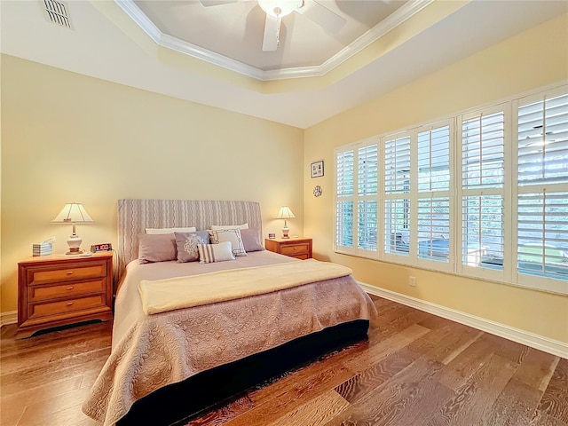 bedroom with crown molding, hardwood / wood-style floors, a raised ceiling, and ceiling fan