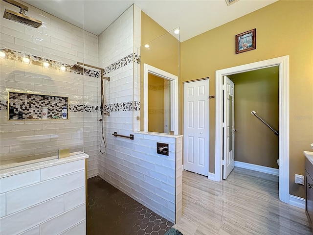 bathroom featuring a tile shower, toilet, and vanity