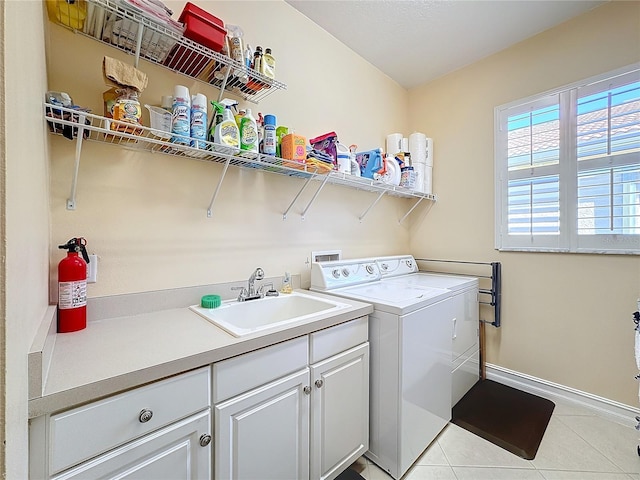 washroom with sink, washing machine and dryer, cabinets, and light tile patterned floors