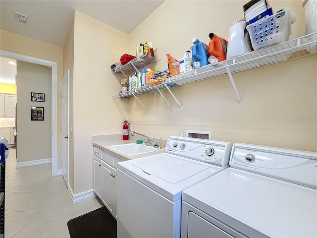 clothes washing area with cabinets, sink, washing machine and dryer, and light tile patterned floors