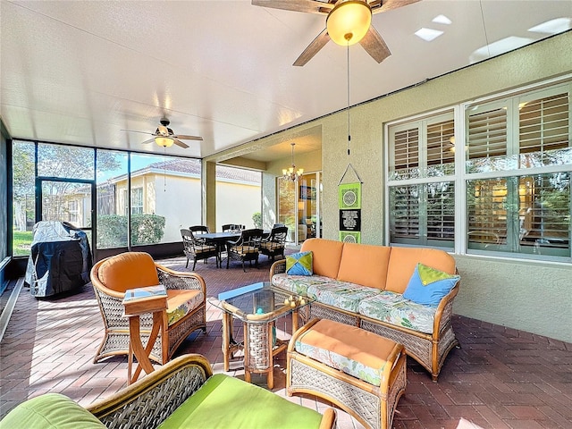 sunroom / solarium featuring ceiling fan with notable chandelier