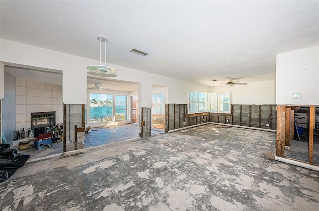 unfurnished living room with ceiling fan, a fireplace, and tile walls