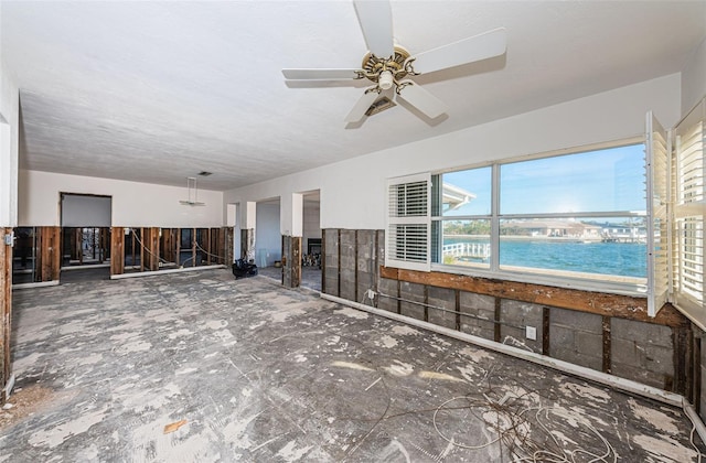 unfurnished living room with a water view and ceiling fan