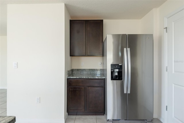 kitchen with stone counters, light tile patterned floors, dark brown cabinets, and stainless steel fridge with ice dispenser