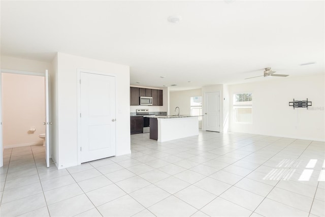 unfurnished living room featuring ceiling fan, sink, and light tile patterned floors