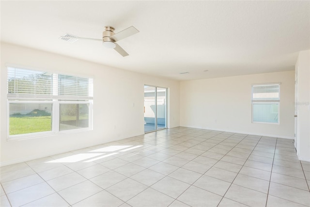 unfurnished room with ceiling fan, light tile patterned floors, and plenty of natural light