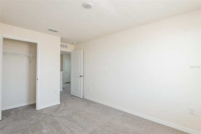 unfurnished bedroom with a closet and light carpet