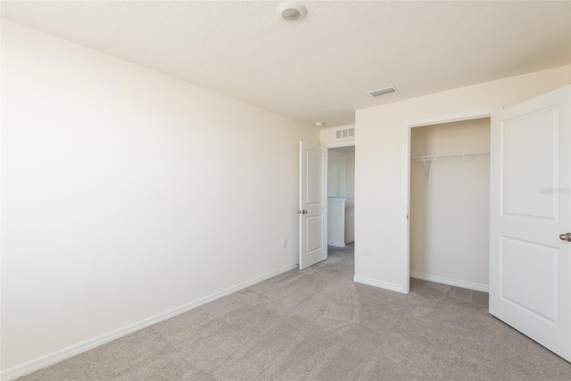 unfurnished bedroom with a closet and light carpet