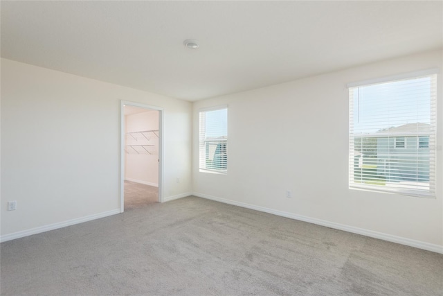 unfurnished room featuring light carpet and plenty of natural light