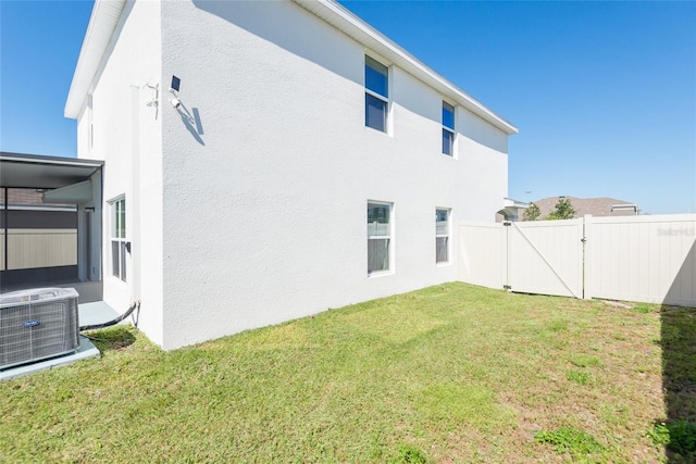 rear view of house with central AC and a yard