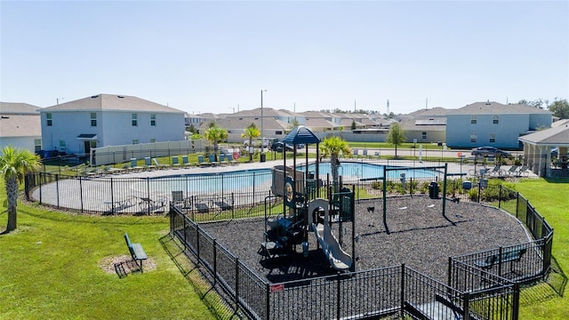 view of jungle gym featuring a community pool and a lawn