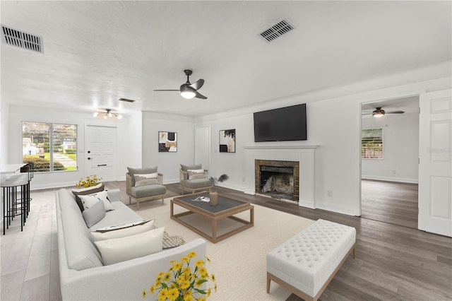 living room with hardwood / wood-style floors, a tile fireplace, and ceiling fan