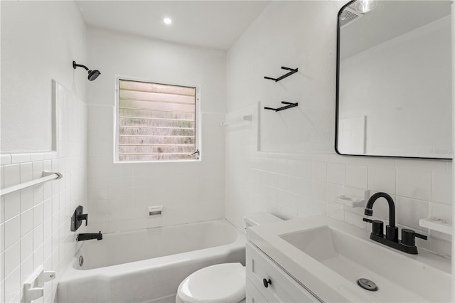 full bathroom with vanity, toilet, tiled shower / bath combo, and tile walls