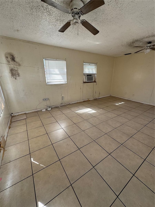 tiled empty room with a textured ceiling, ceiling fan, and a wealth of natural light