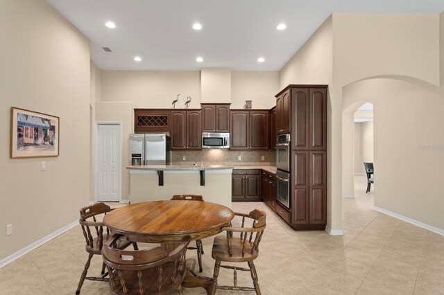 3320 Majestic View Dr, Lutz, FL 33558 - kitchen featuring stainless steel appliances, arched walkways, dark brown cabinets, backsplash, and recessed lighting